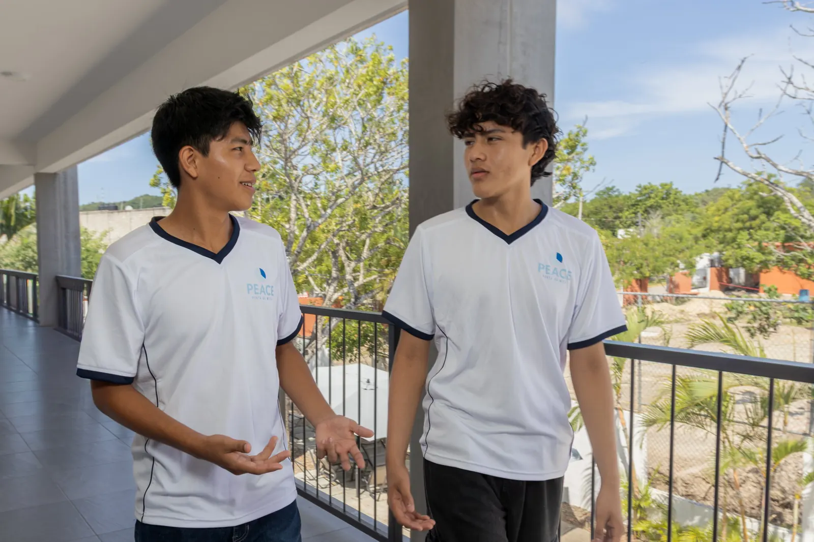 Two PEACE Punta de Mita students talking as they walk along a terrace at Campus de Mita