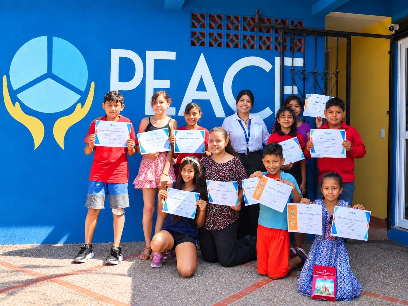 PEACE Punta de Mita students proudly holding their certificates in front of the PEACE mural
